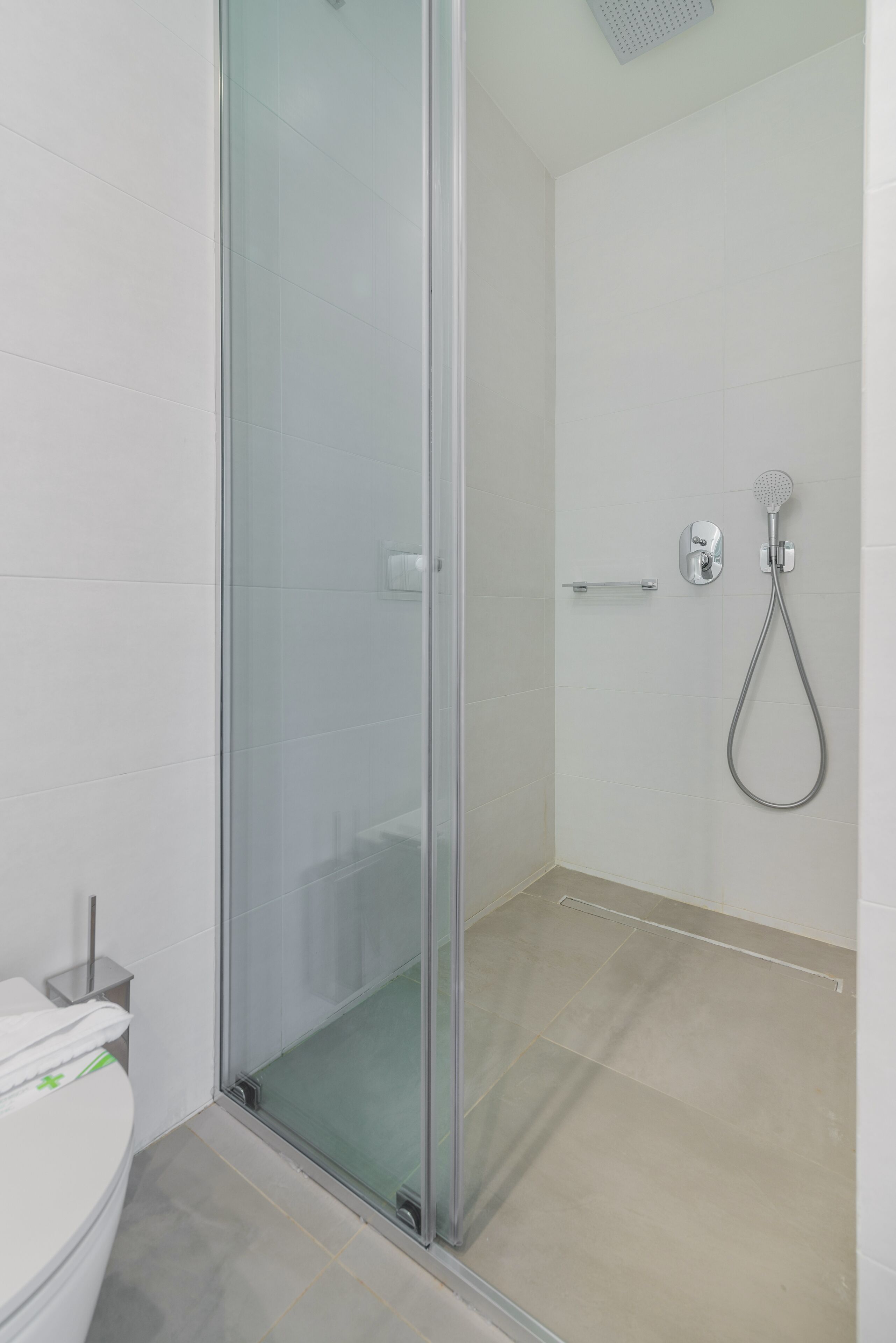 Ein modernes Badezimmer mit Duschkabine aus Glas, Toilette und Handbrause.