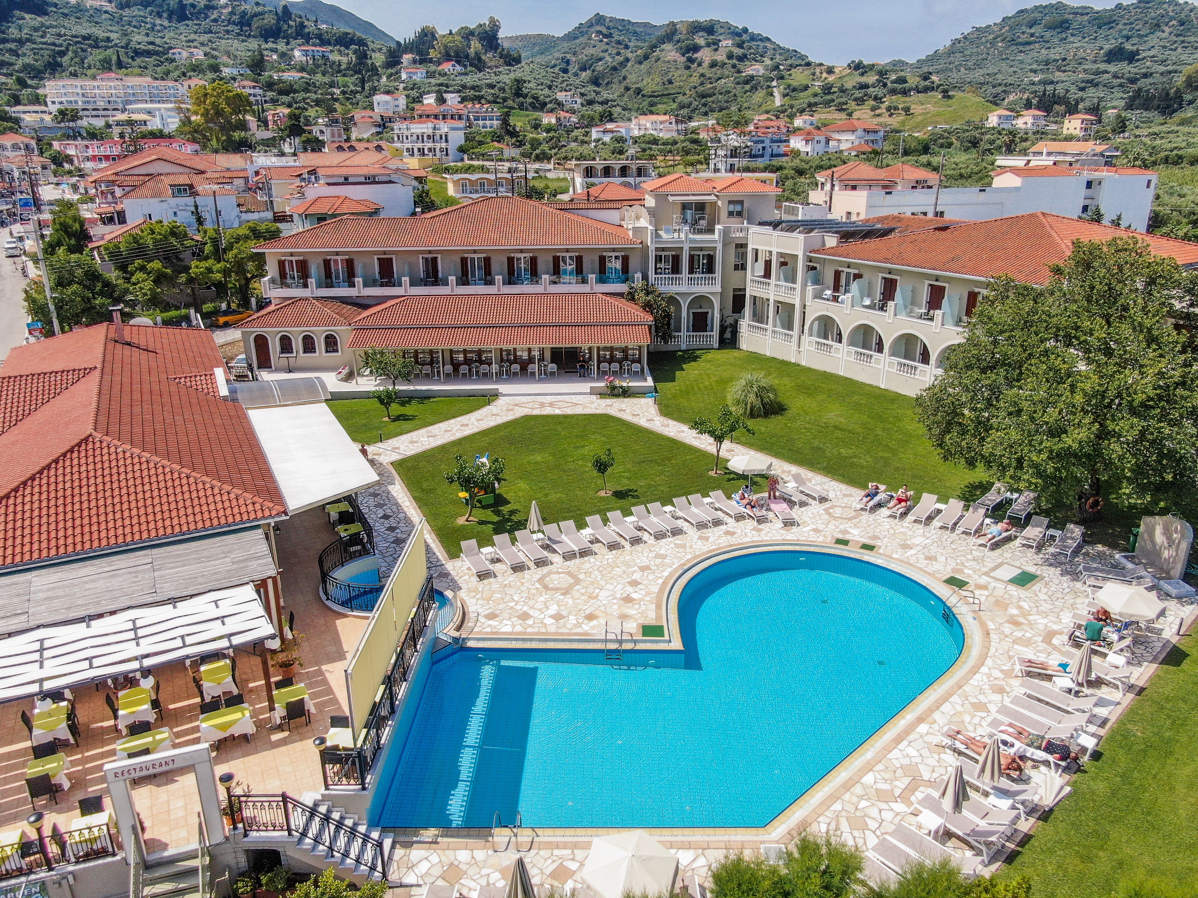 Un hotel con piscina, mobiliario exterior y vistas del pueblo circundante.