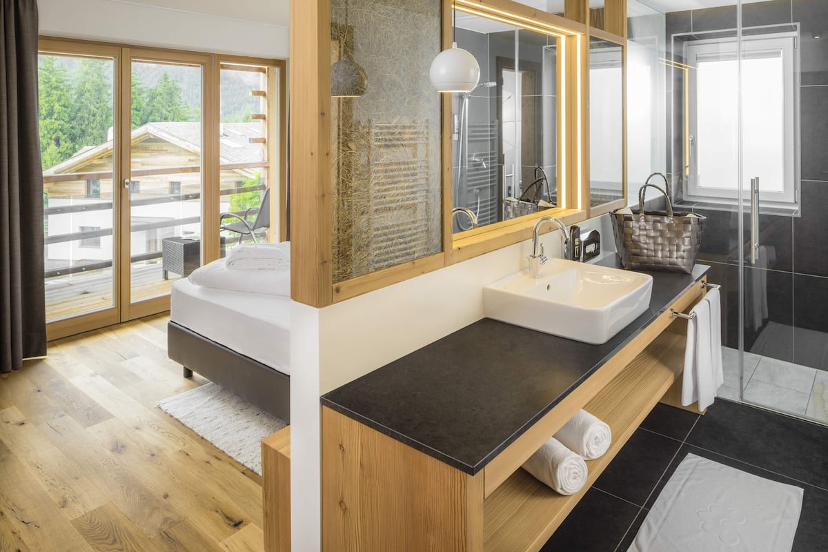 Un baño moderno con lavamanos doble, tocador de madera y un espejo grande.