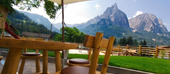 A wooden outdoor seating area with a view of mountains. - Hotel Arvina (Castelrotto)