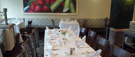 A restaurant with a long dining table set for a meal, surrounded by chairs.