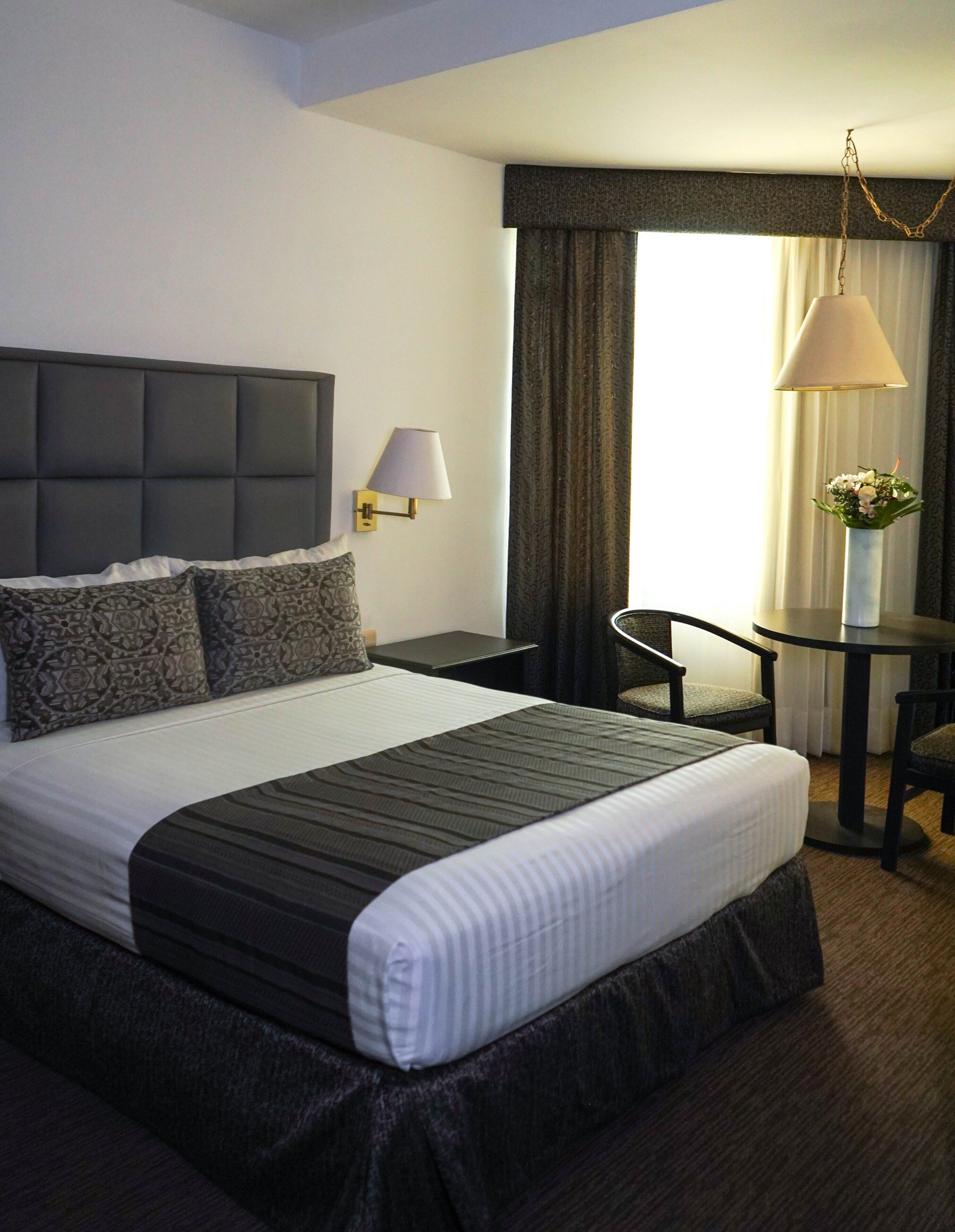 Une chambre d’hôtel avec un grand lit, un bureau, une chaise et une lampe.