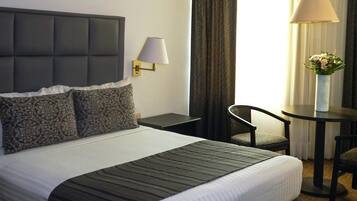 Une chambre d’hôtel avec un grand lit, un bureau, une chaise et une lampe.