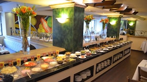 A buffet with various food items and a floral centerpiece. - Hotel San Marcos Grand (Culiacán)