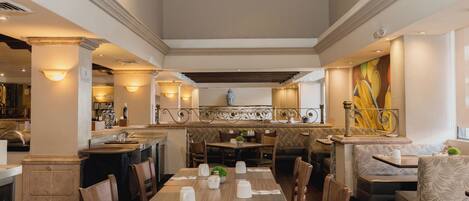 A restaurant with a high ceiling, wooden tables, and cushioned seating.