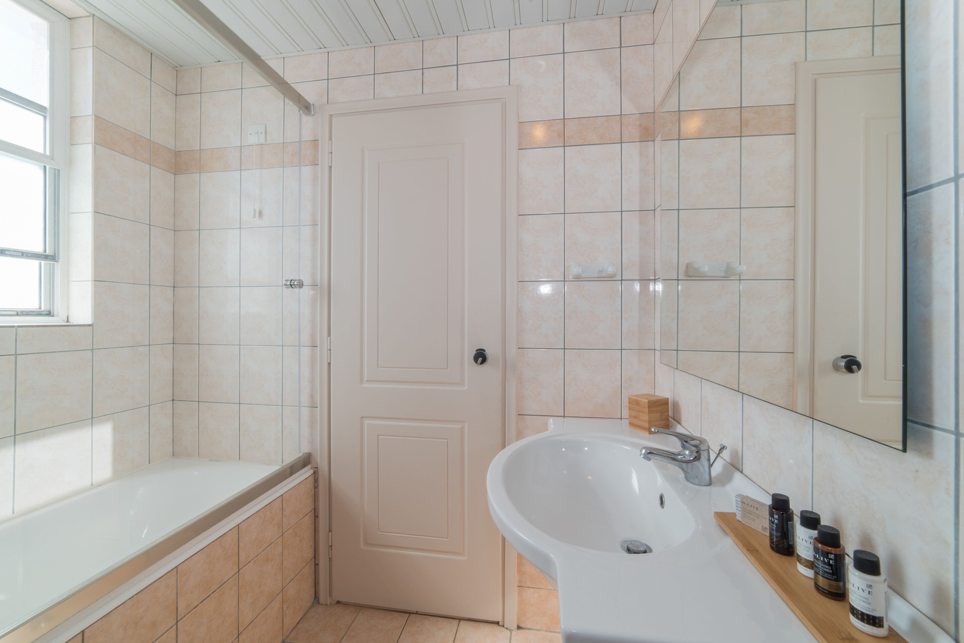A bathroom with a bathtub, a sink, and a mirror.