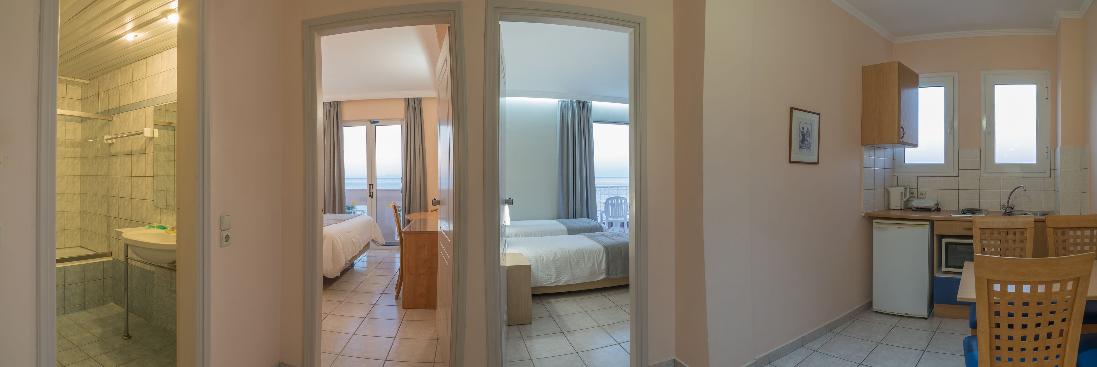 Una habitación de hotel con baño, cama, escritorio y kitchenette.