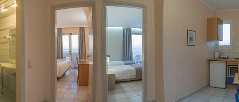 Una habitación de hotel con baño, cama, escritorio y kitchenette.