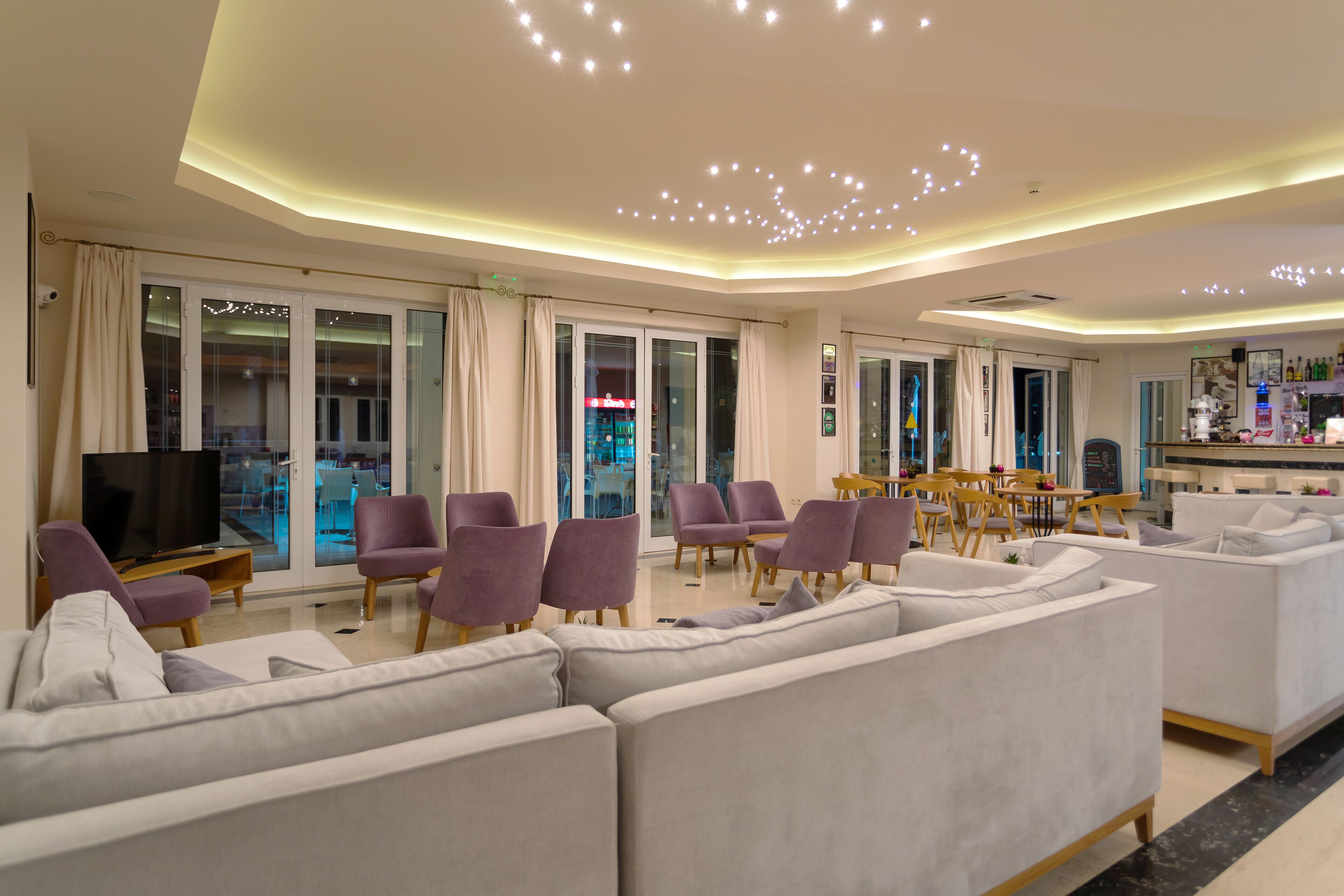 Een moderne woonkamer met een grote bank, paarse fauteuils en een televisie.