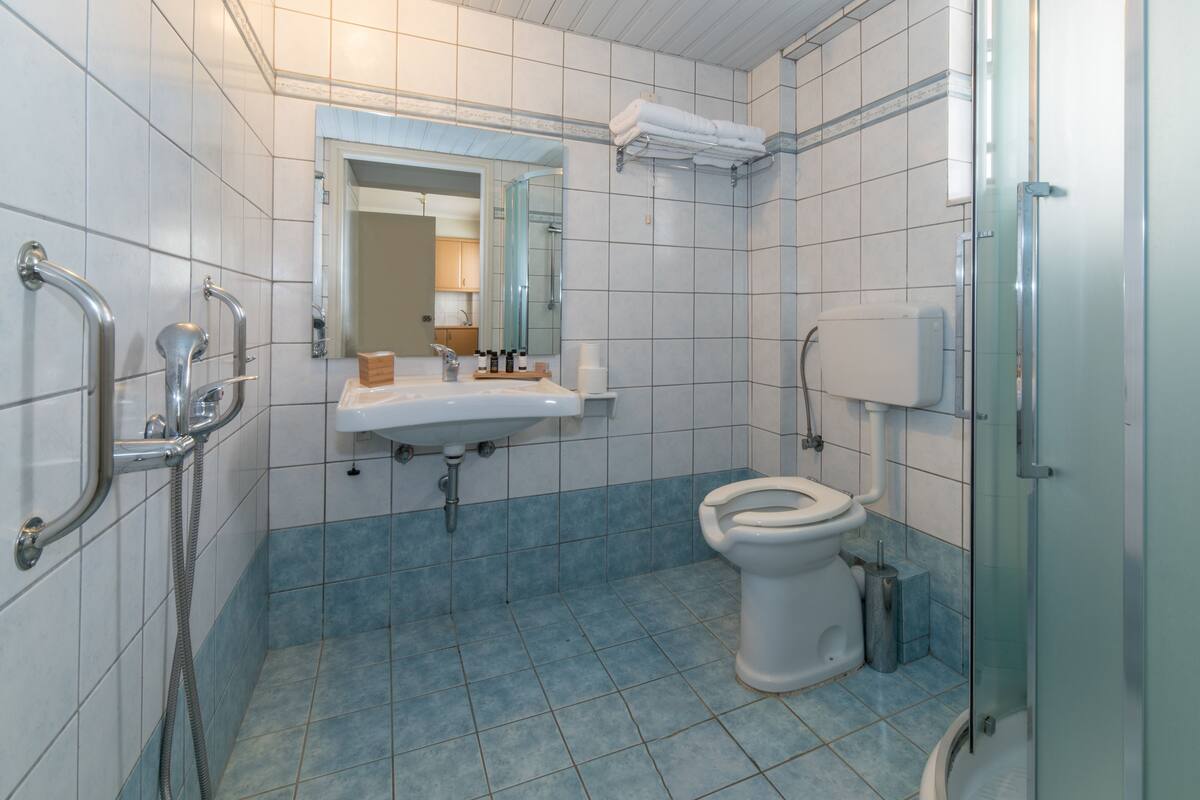 Un baño con lavamanos blanco, inodoro y zona de ducha.