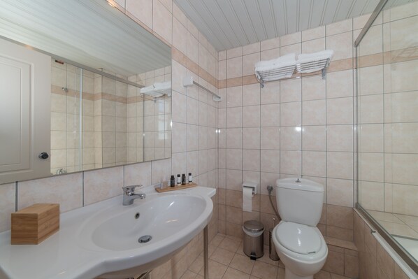 Un baño con lavamanos, espejo, inodoro y toallero.