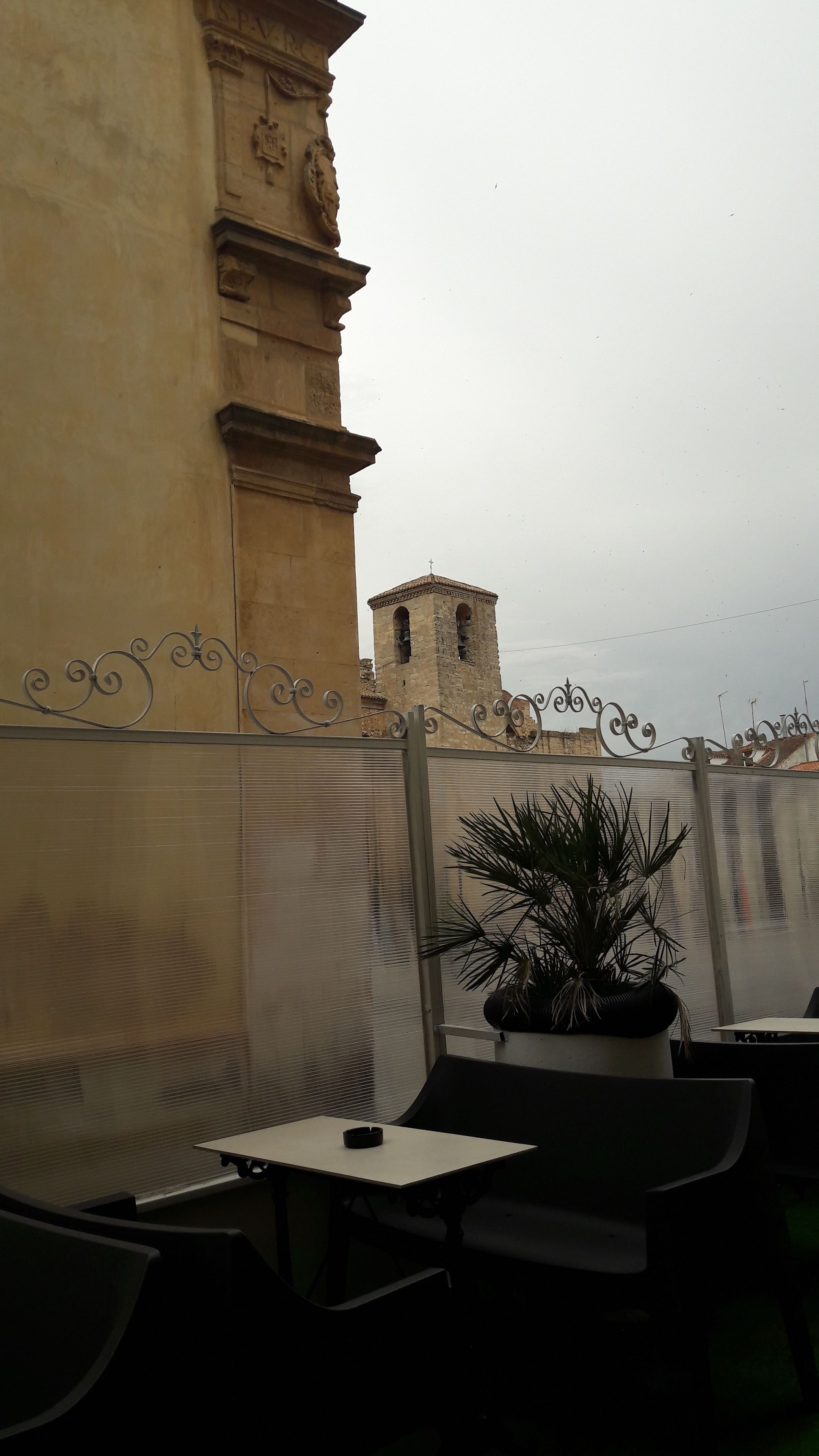 Un espacio con mesas al aire libre que ofrece vistas a un edificio histórico y una torre.