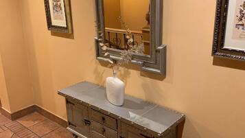 Un tocador de estilo vintage con un espejo grande, un jarrón blanco y un mueble metálico con cajones.