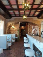 Un interior de restaurante con arcos de piedra, cabinas blancas y una zona de bar.