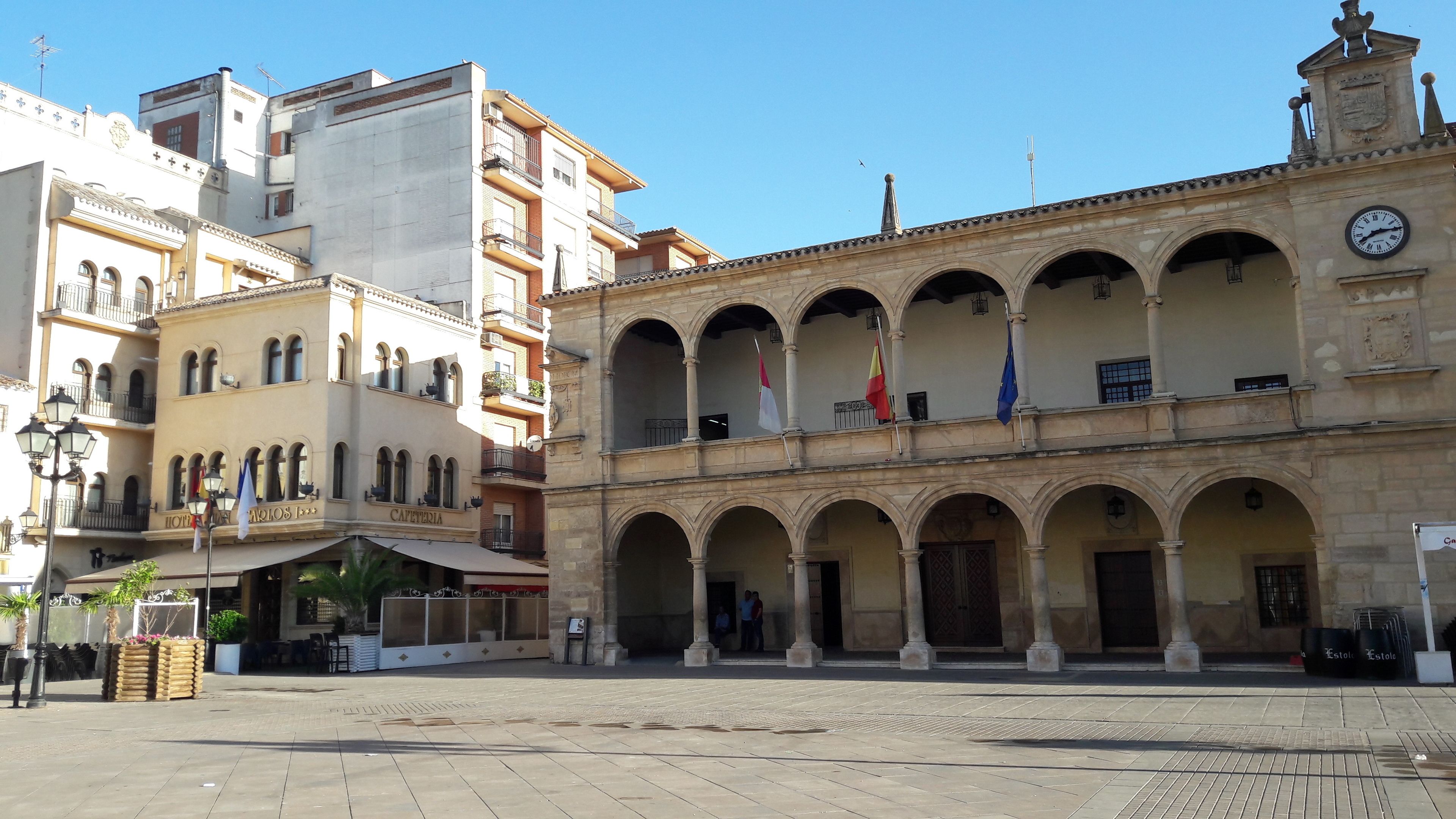 Un edificio histórico con una torre de reloj, varios arcos y banderas.
