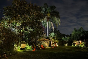 A garden with a swing chair, a covered seating area, and a palm tree. - Areté (Tepoztlán)