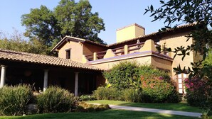 A traditional building with a covered patio, a brick chimney, and a well-maintained garden with various plants and a pathway. - Areté (Tepoztlán)