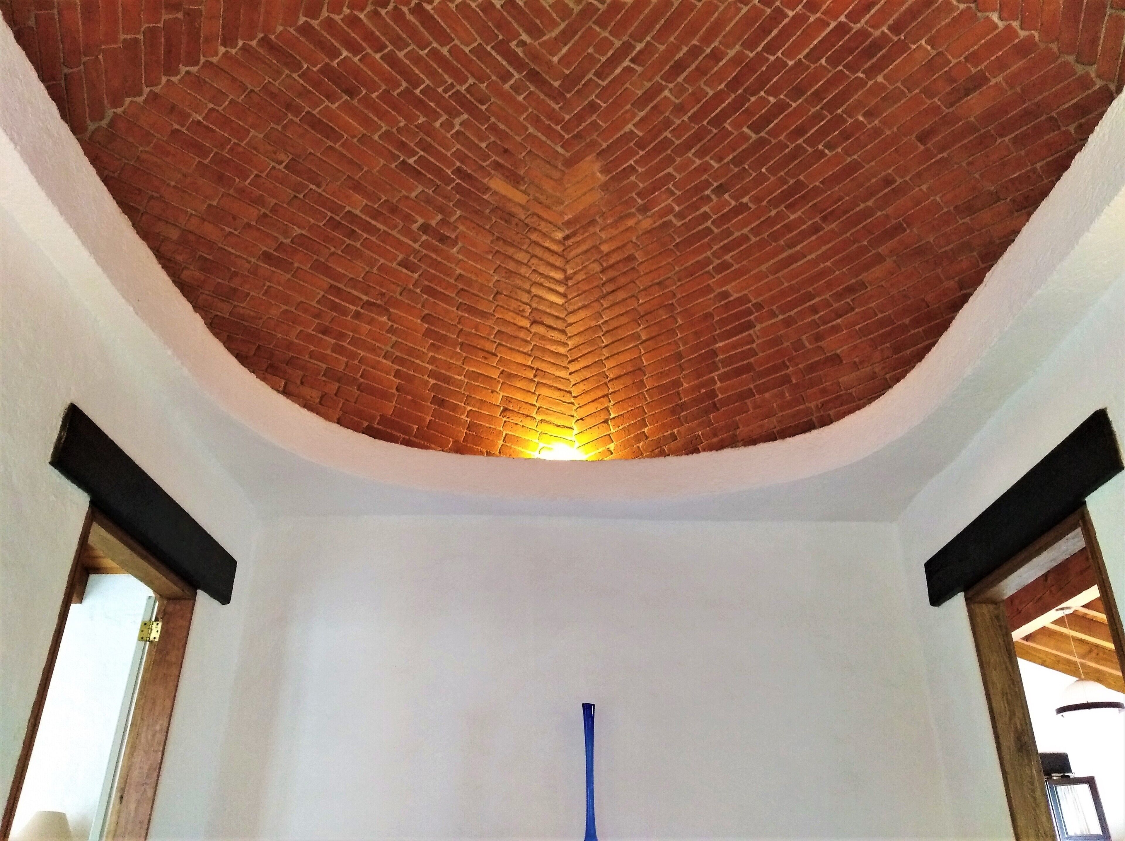 A room with a brick ceiling, white walls, and a blue object in the center.