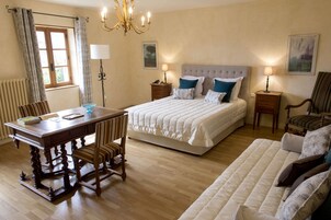 Un dormitorio con una cama doble, un escritorio de madera, una silla, una mesita de noche, una lámpara, un radiador y una ventana con cortinas.