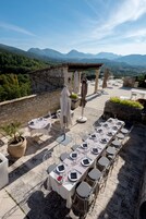 Un espacio de comedor al aire libre con mesas, sillas, sombrillas y plantas en macetas.