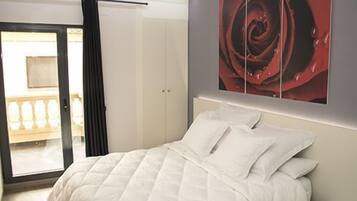 Un dormitorio con una cama, una puerta y un cuadro grande de una rosa.