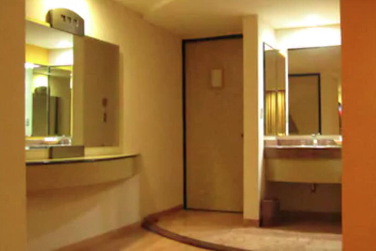 Een hotelbadkamer met een wastafel, spiegel en toilet.