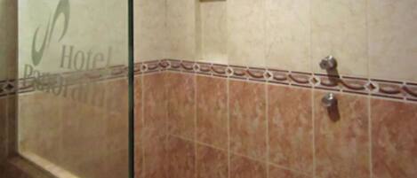 A bathroom with a tiled wall, a shower area, and a visible showerhead.