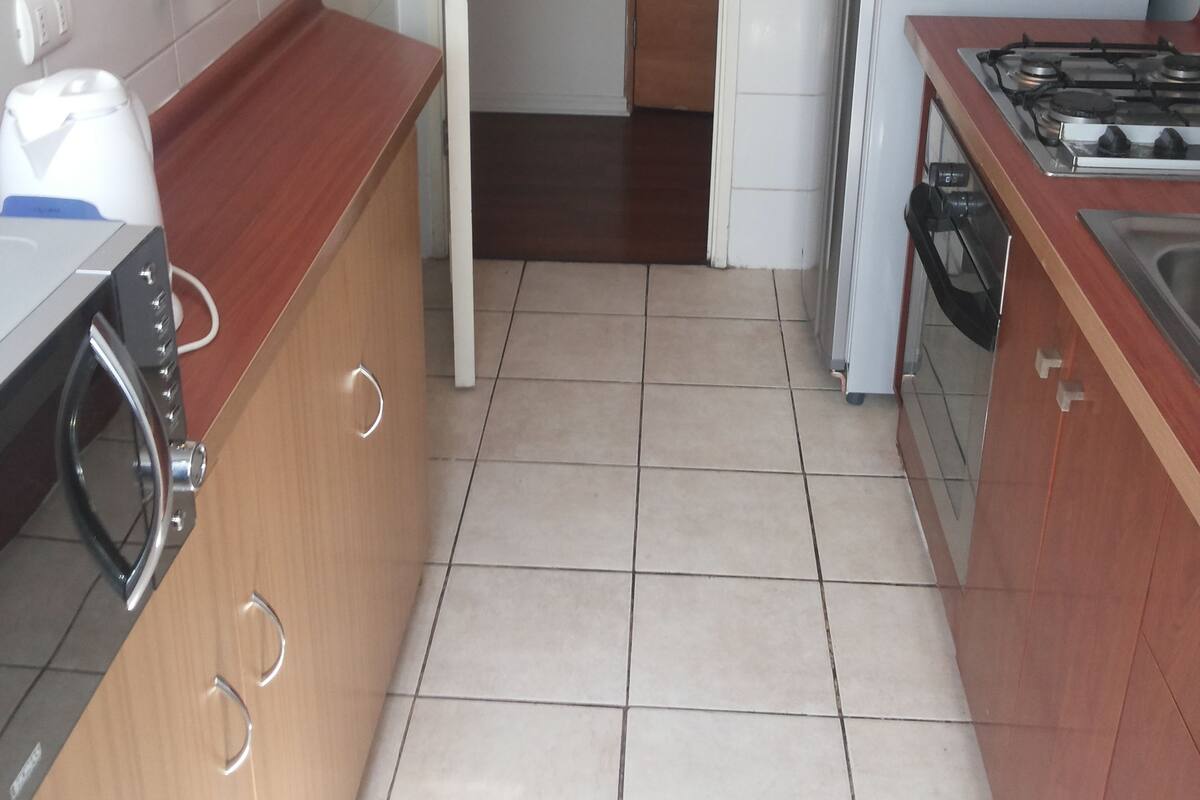 A kitchen with a microwave, stove, and refrigerator. There is a wooden countertop and a tiled floor.
