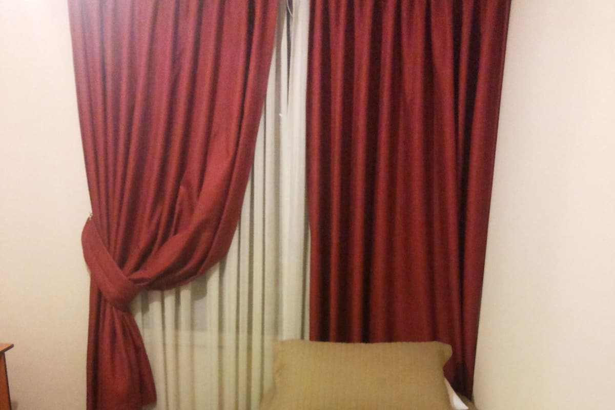 A small, single-bed room with a beige bedspread and two pillows.