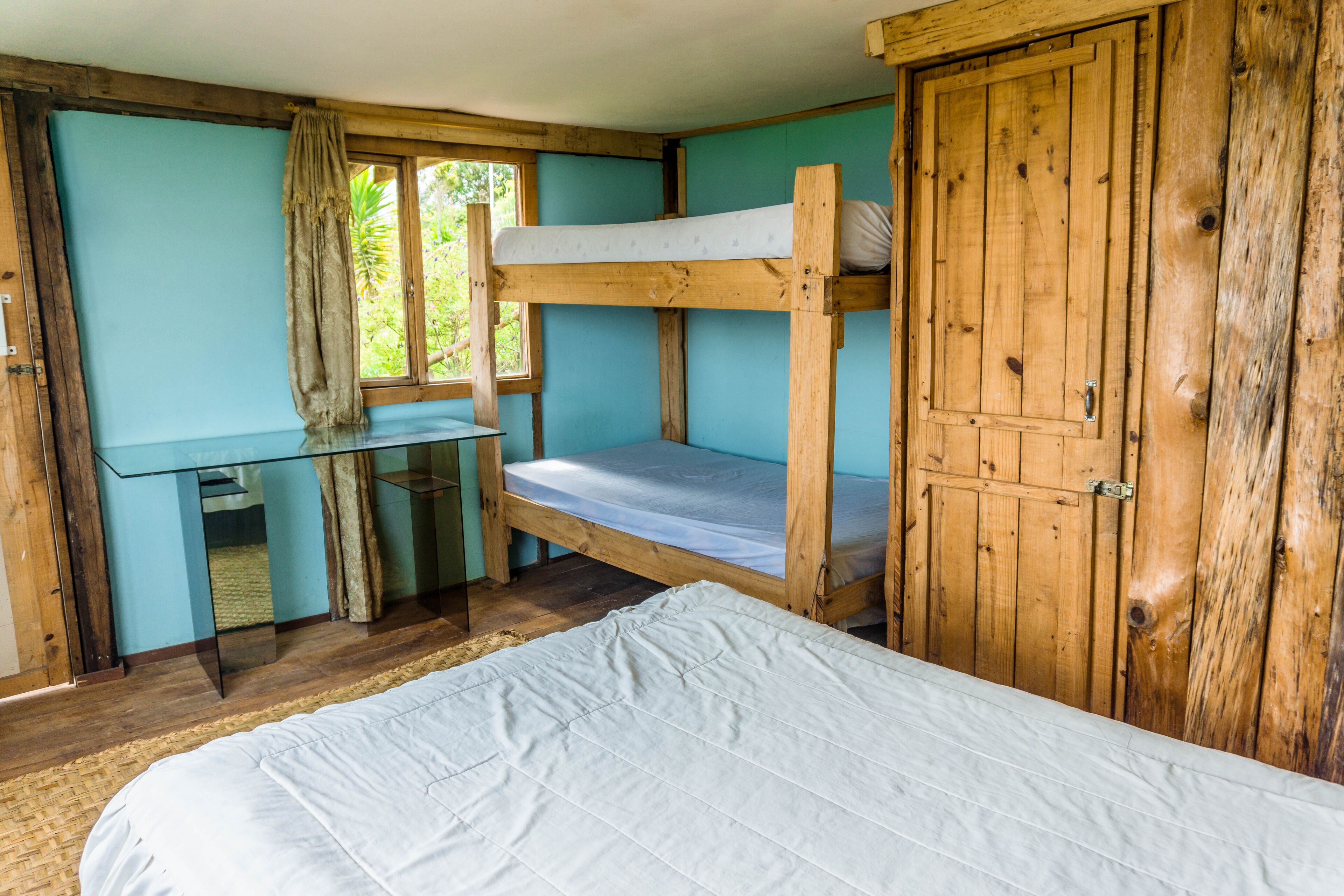 A bunk bed room with a desk and a wardrobe.
