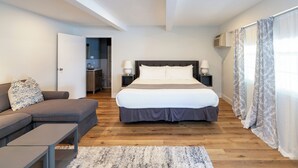 A modern bedroom with a large bed, a sofa, and a small table. - Iron Masters - Inn on Main (Lakeville)