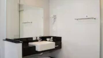 A modern bathroom with a white sink, dark countertop, and wooden flooring.