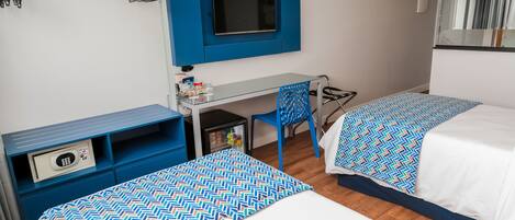 Une chambre d’hôtel avec deux lits, un bureau, une chaise, une télévision et une armoire.