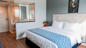 Una habitación de hotel con una cama grande, una mesita de noche, un espejo y un cuadro en la pared.