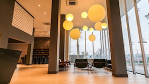 Een ruime lobby met modern licht, een receptiebalie en grote ramen met uitzicht.