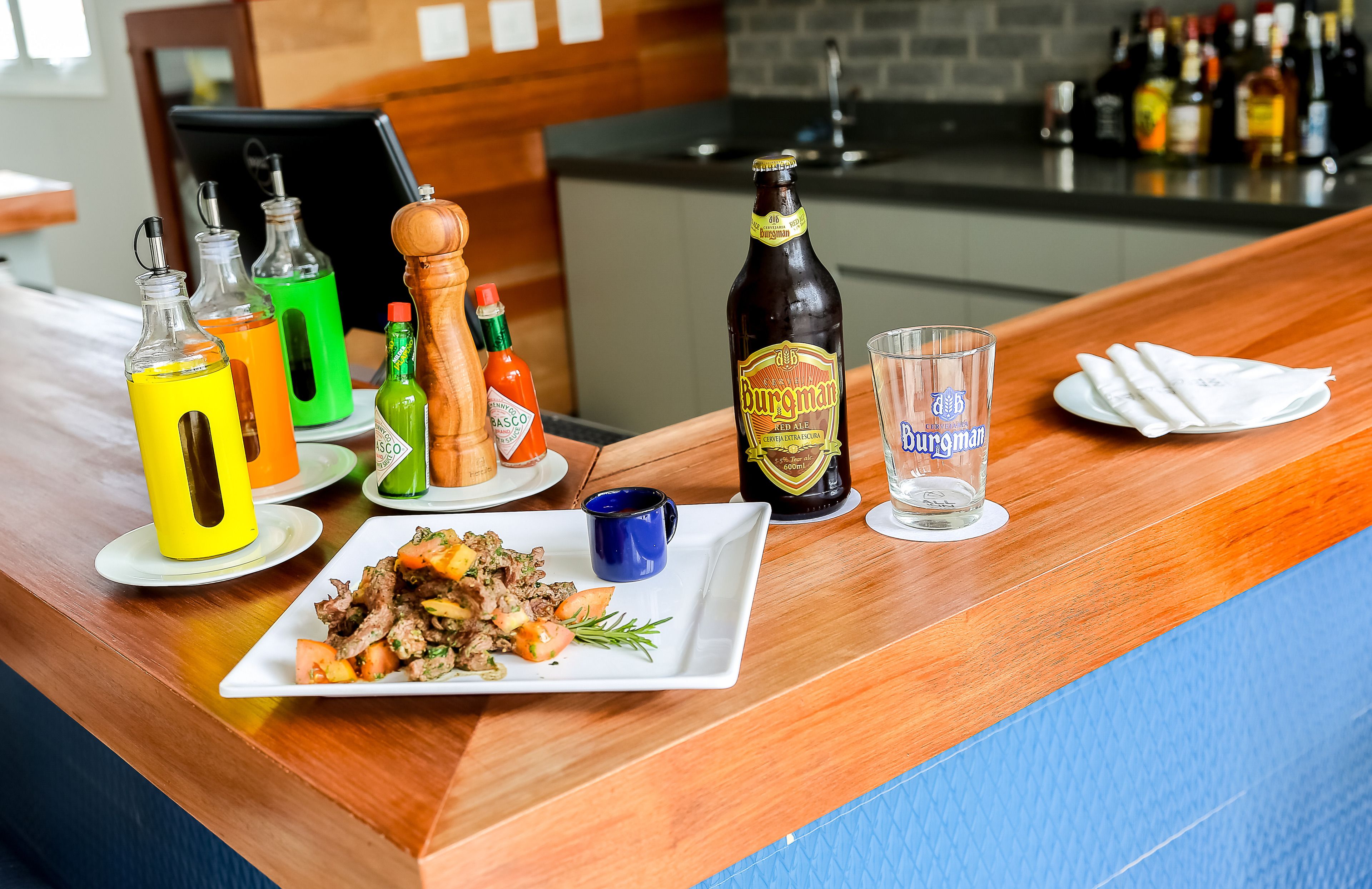 A bar area with a variety of bottles, a plate of food, and a glass.