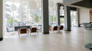 Een ruime lobby met modern meubilair, grote ramen en een trap.