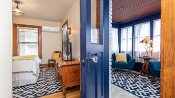 Una habitación con una cama, un escritorio, una silla, un sofá azul y una alfombra estampada.
