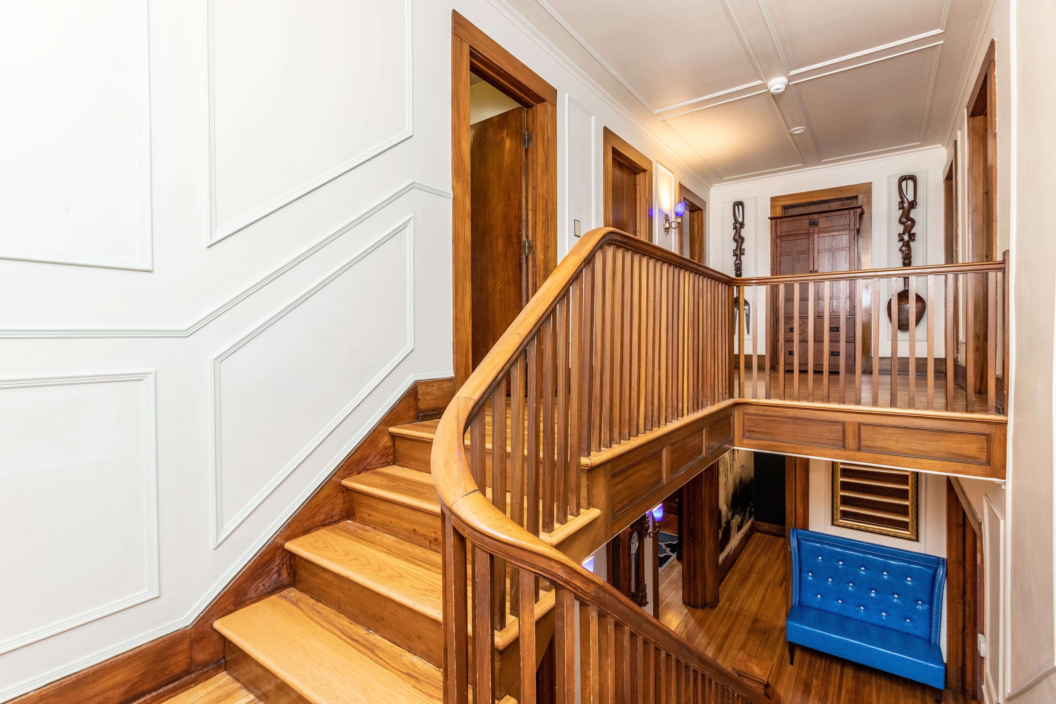 A wooden staircase with a blue bench at the bottom landing.