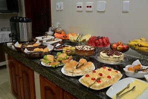 A buffet with various food items including sandwiches, cakes, and fruits. - Rede Andrade Frota Palace Hotel (Macapa)