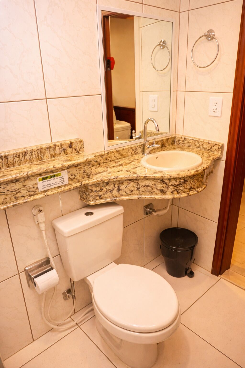 Une salle de bain avec un lavabo surmonté d’un plan de travail en marbre, des toilettes, un bidet et une poubelle.