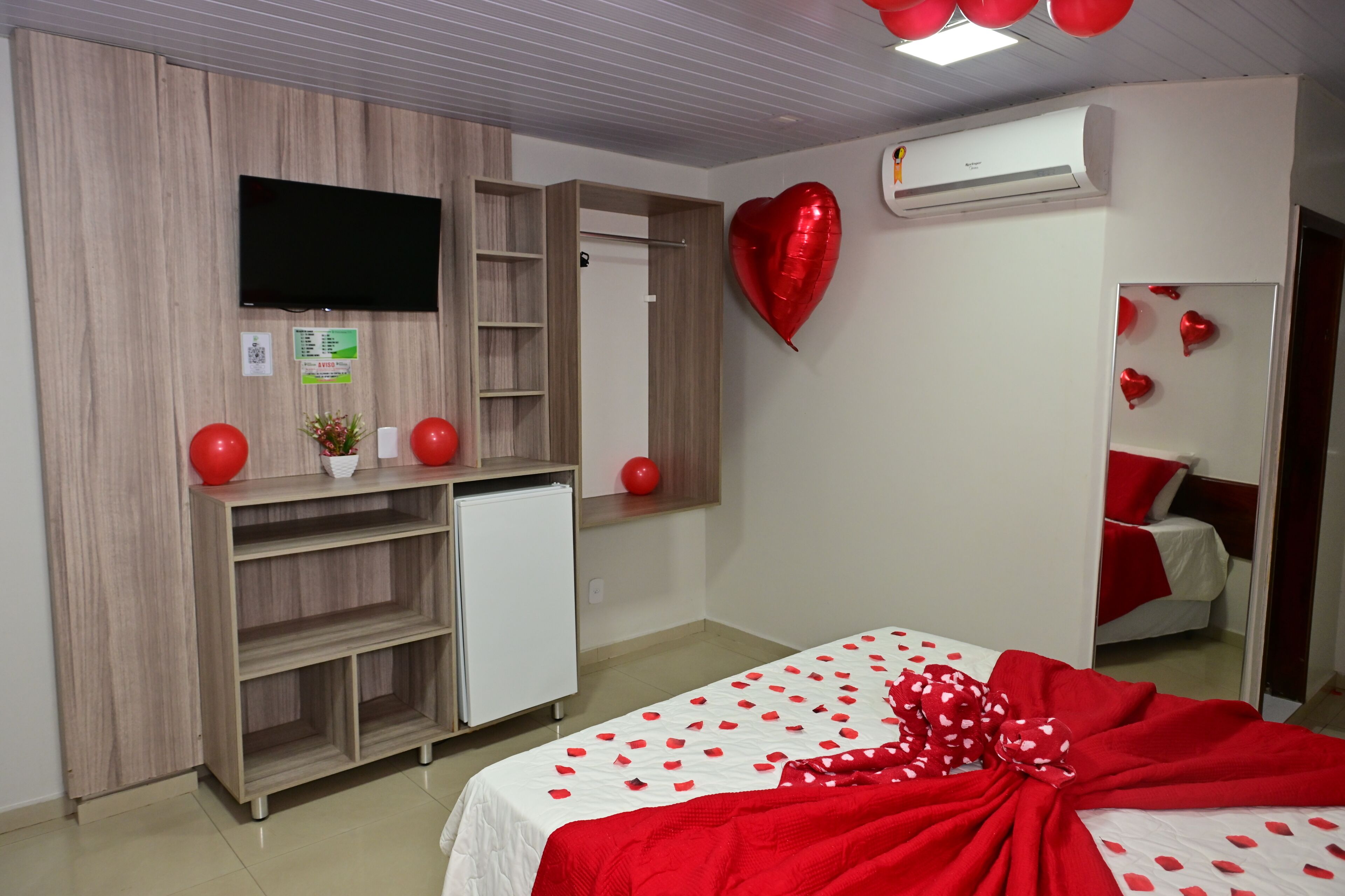 A bedroom with a bed, a TV, a wardrobe, and a mirror.