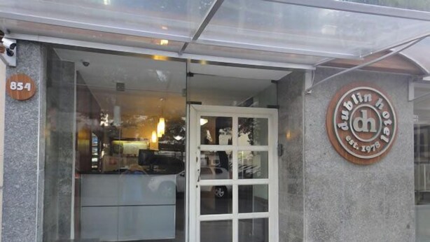 A hotel entrance with a glass door, a sign with the hotel's name and establishment year, and a number sign above the door. - Hotel Dublin (São Paulo)