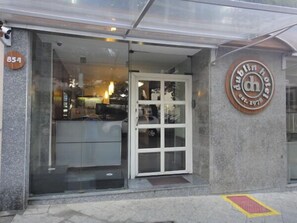 A hotel entrance with a glass door, a sign with the hotel's name and establishment year, and a number sign above the door. - Hotel Dublin (São Paulo)
