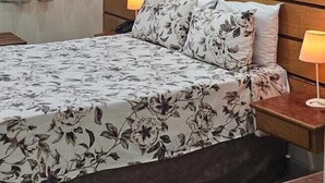 A hotel room with a bed, a nightstand, a ceiling fan, an air conditioning unit, and a marble-patterned wall. - Hotel Dublin (São Paulo)