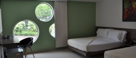 Una habitación de hotel con una cama, un escritorio y dos ventanas.