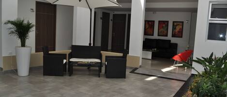 A spacious lobby with a seating area, a large potted plant, and artwork on the walls.