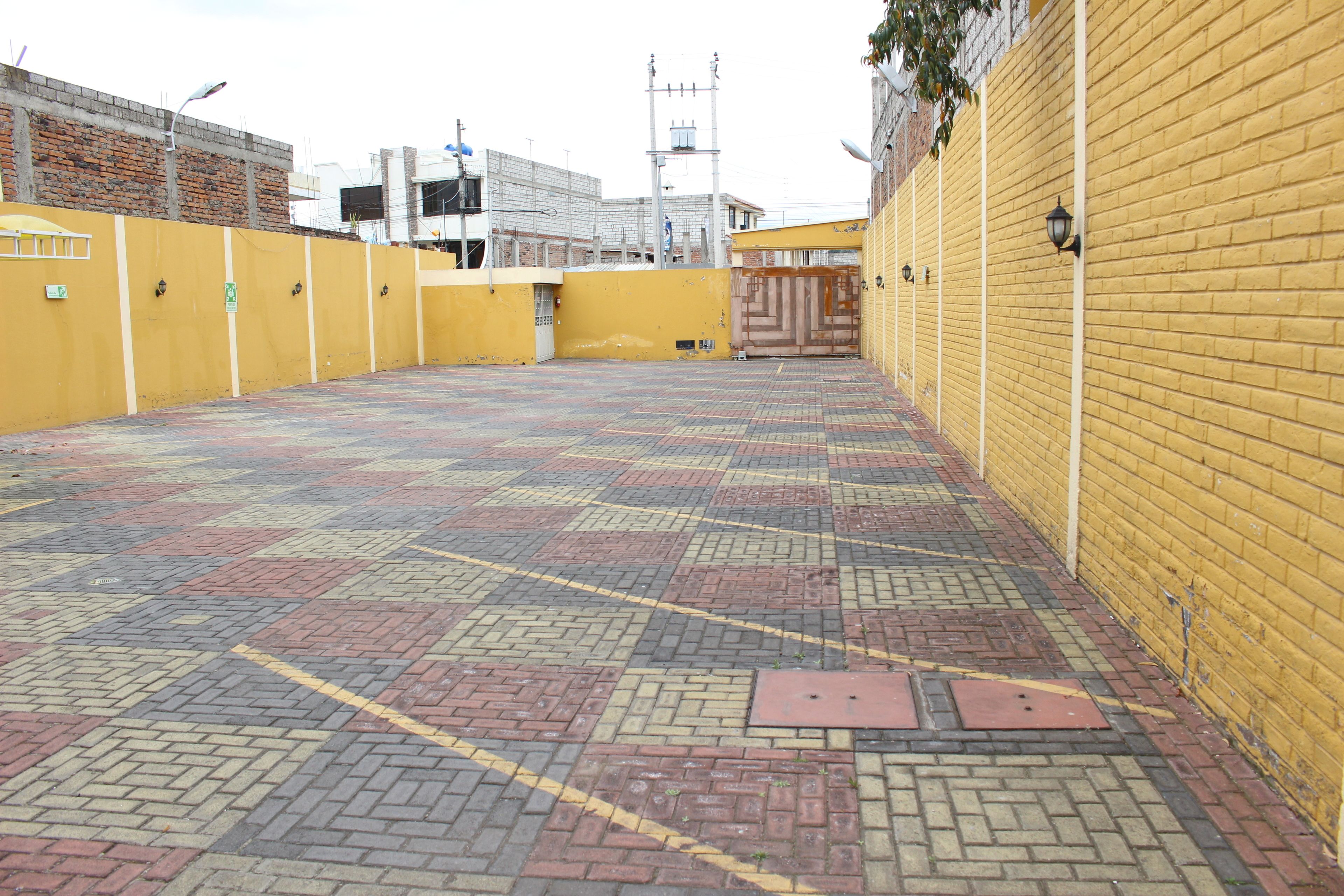 A paved outdoor area with yellow walls and a brick pattern floor.