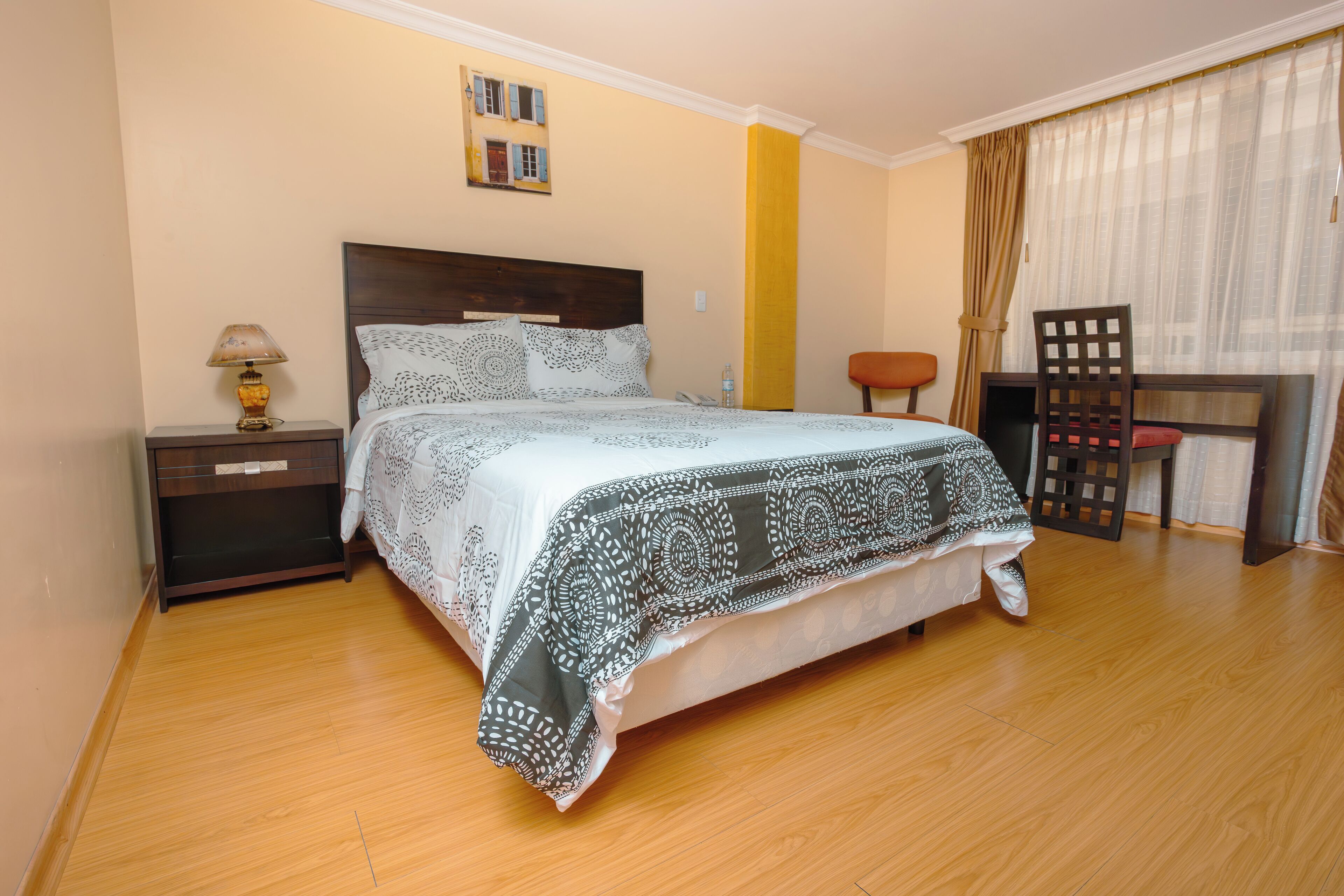 A neatly arranged bedroom with a bed, nightstand, desk, and chair.