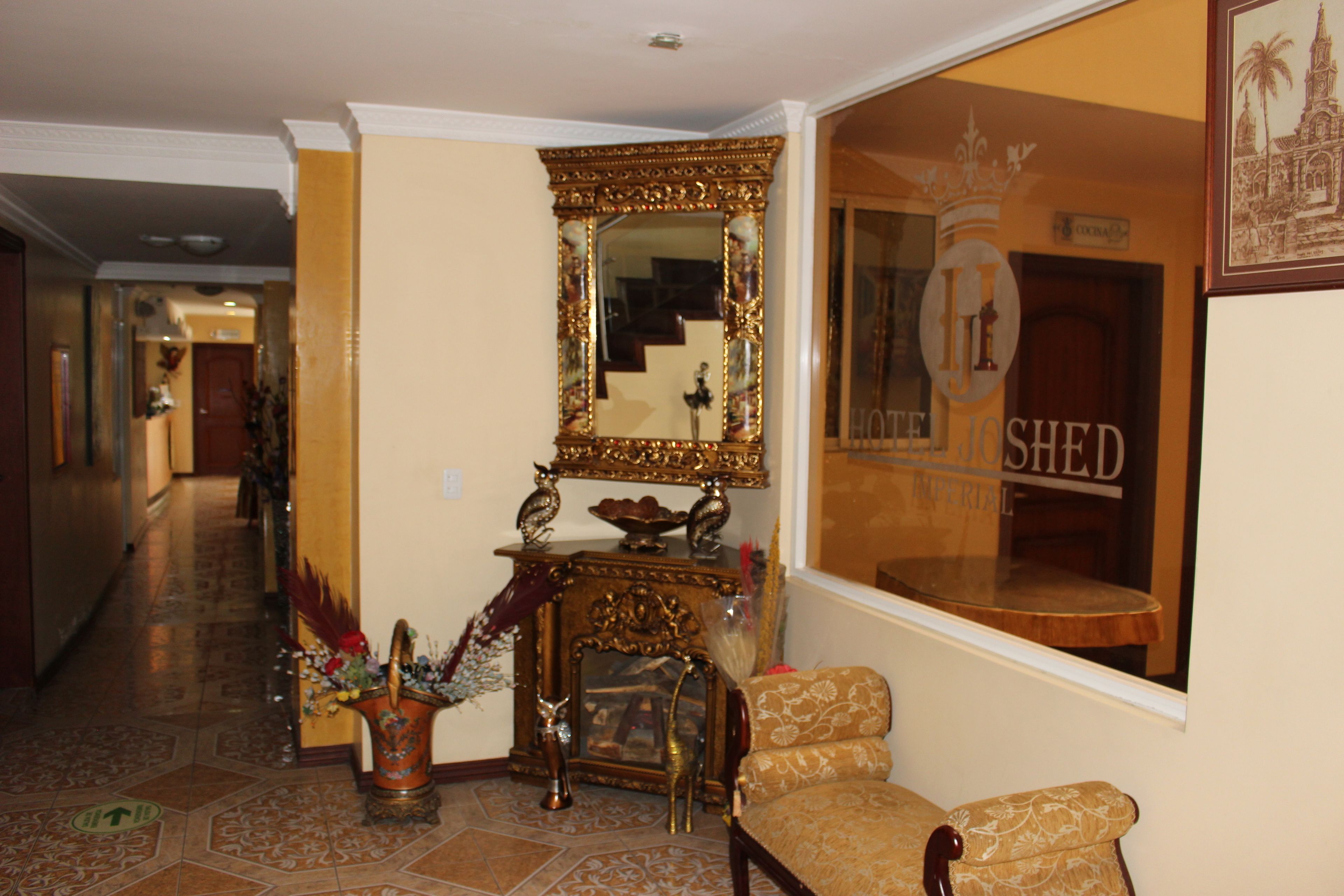 A hallway with a large mirror, a sofa, and a decorative vase.